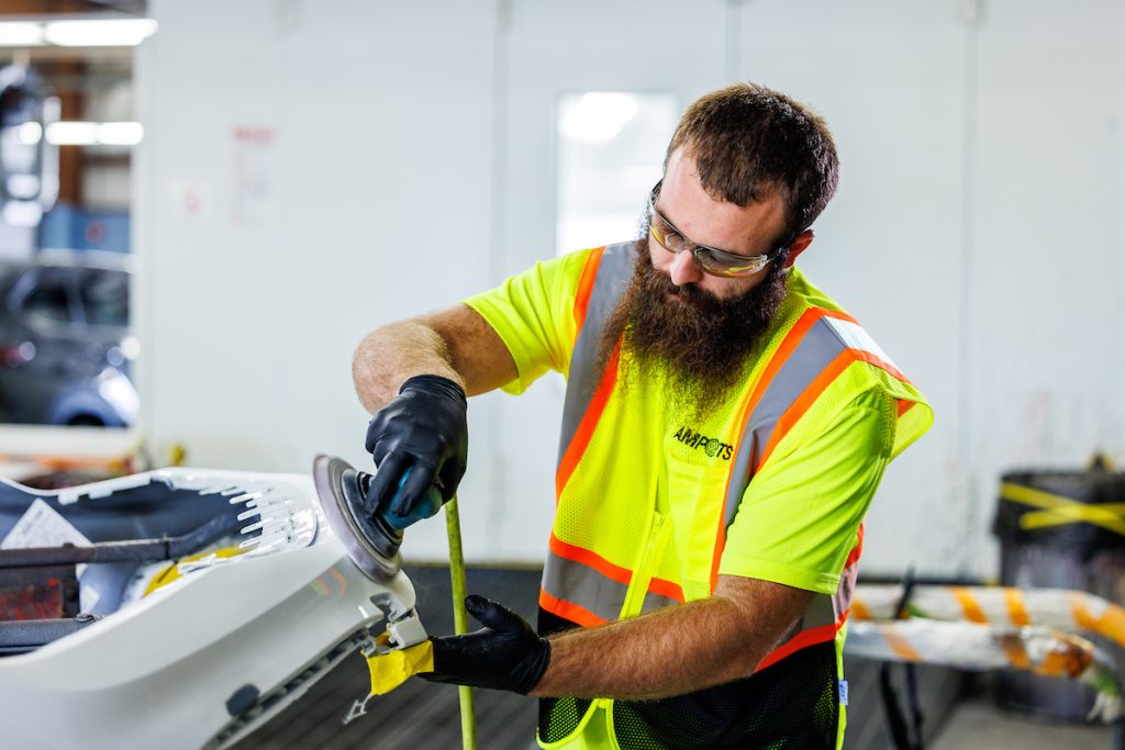 Amports staff wearing a safety vest and glasses, polishing a car