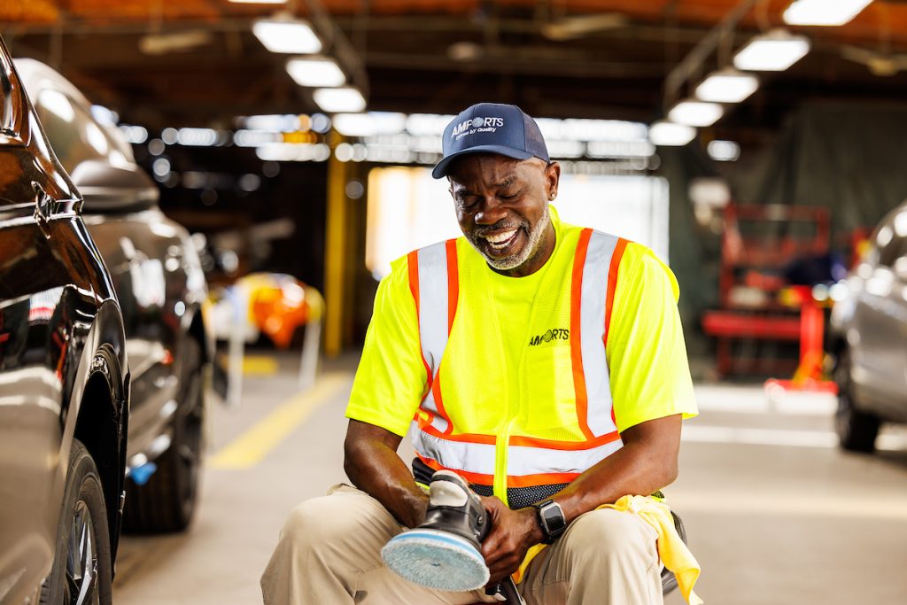 A portrait of a smiling Amports staff holding a car polisher