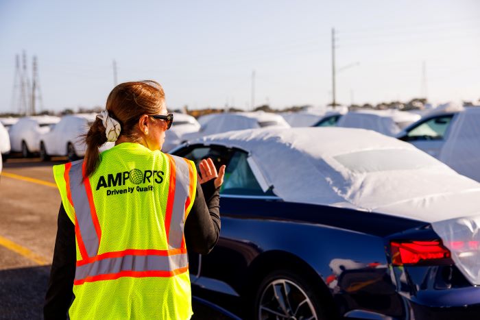 Amports worker spotting a car in an outdoor parking lot