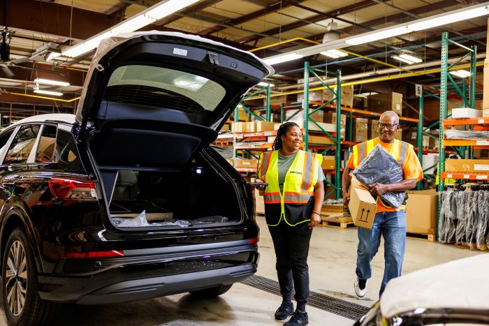 Two Amports workers having a conversation near an open SUV trunk at a warehouse